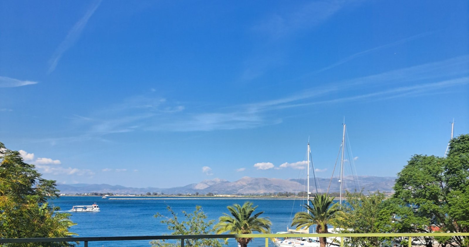 The harbour of Nafplio with palm trees, sailing boats and mountains